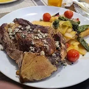 Un plato blanco cubierto con carne y verduras sobre una mesa.