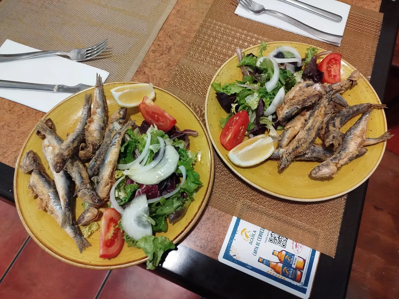 Dos platos de comida en una mesa que incluyen pescado y ensalada.