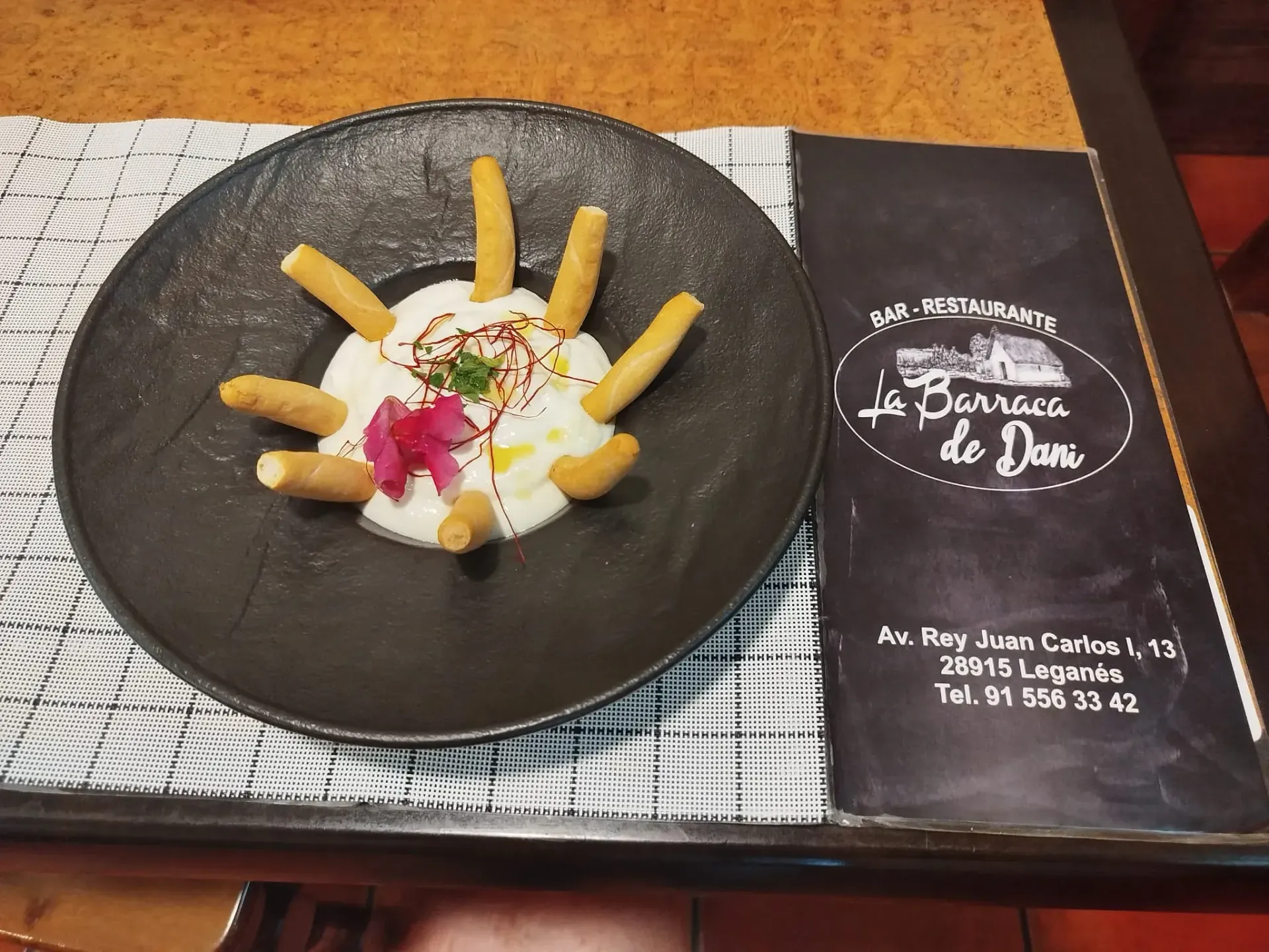 Un plato de comida está en una mesa junto a un menú.