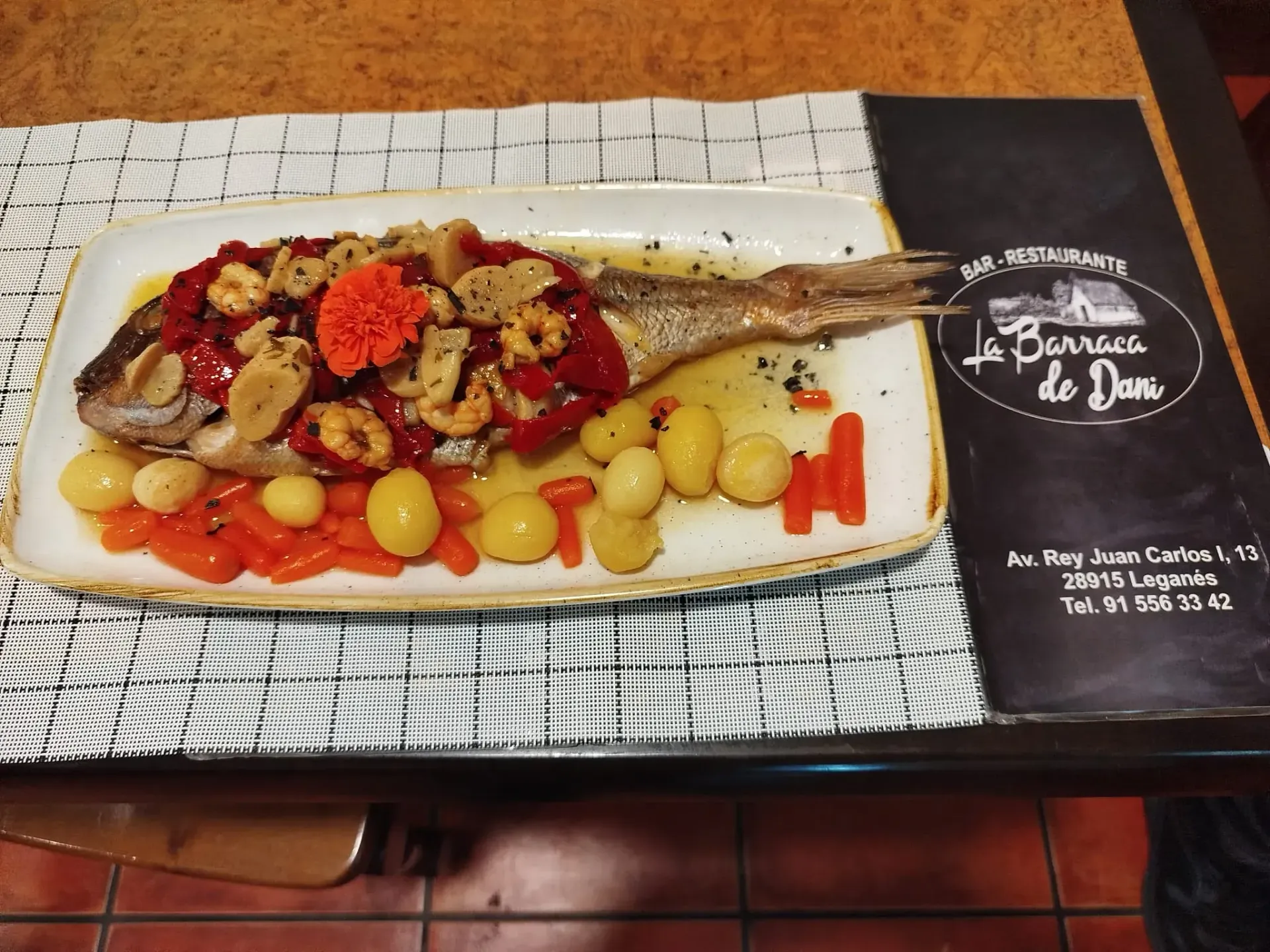 Un plato de comida en una mesa con un menú al fondo.