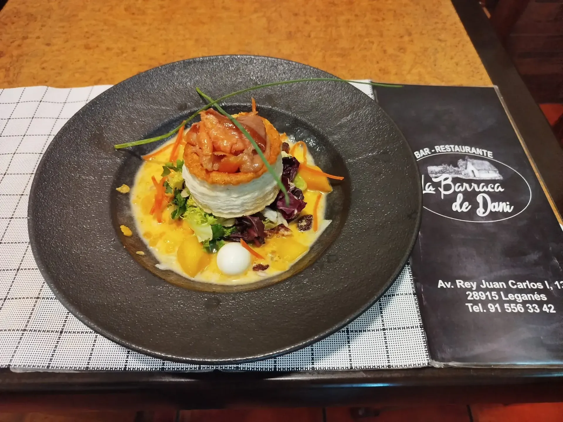 Un plato de comida se encuentra en una mesa junto a un menú.