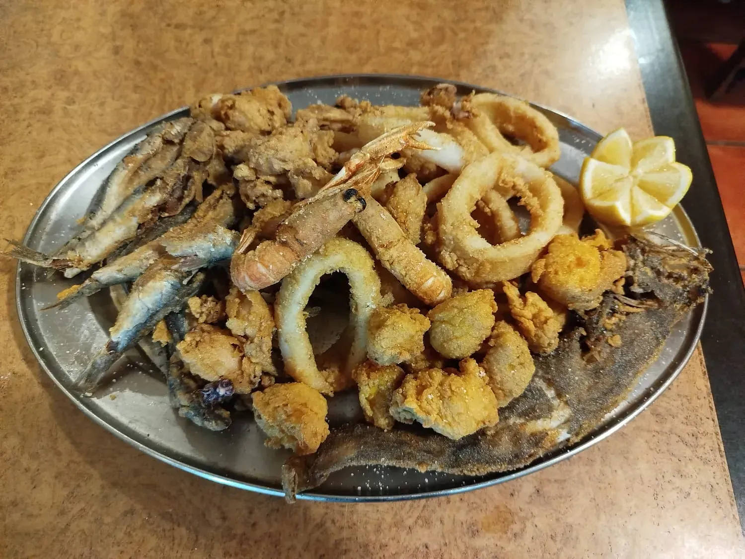 Un plato de mariscos fritos con una rodaja de limón sobre una mesa.