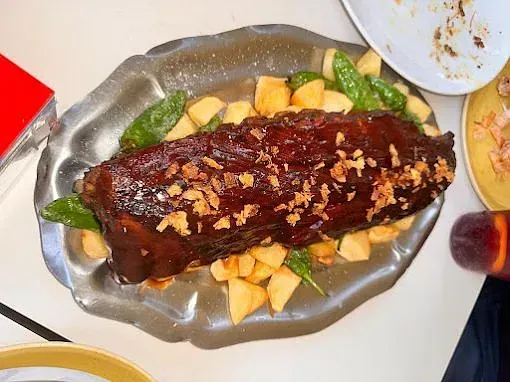 Un plato de comida con costillas y patatas en una mesa.