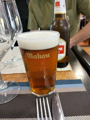 Un vaso de cerveza está sobre una mesa al lado de una botella de cerveza.