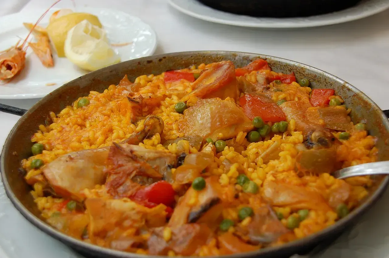 Una sartén llena de arroz y verduras con una cuchara dentro.