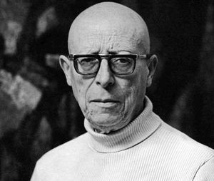 Hombre calvo con gafas y cuello alto.