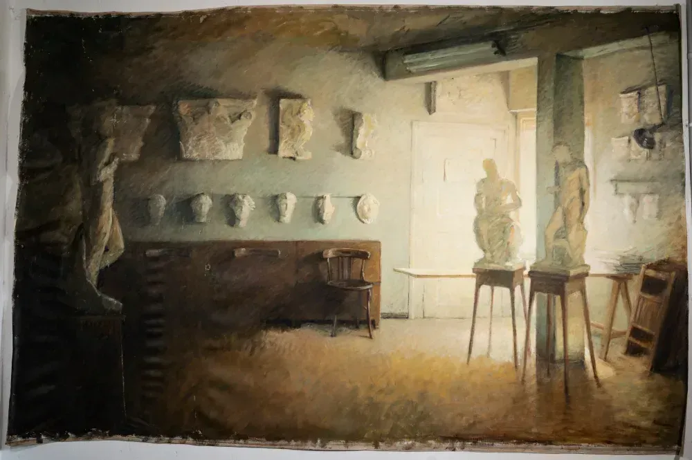 Interior de un estudio de arte con esculturas, moldes de yeso y brillante luz natural.