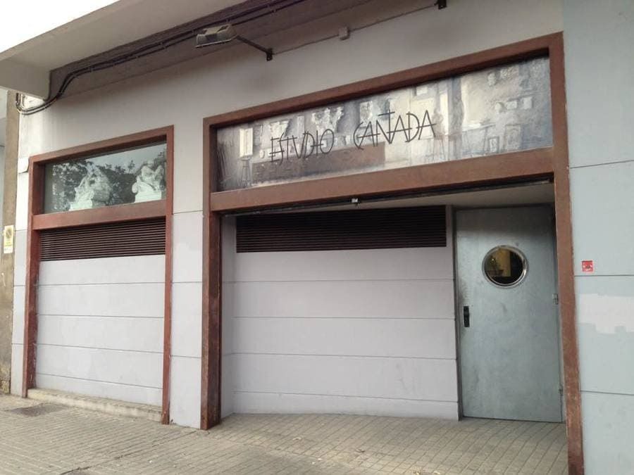 Vista exterior de un edificio con puerta blanca, ventanas y molduras marrones. El texto sobre la entrada no es claro.