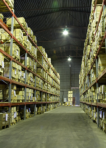 Interior de almacén con estantes altos repletos de cajas.