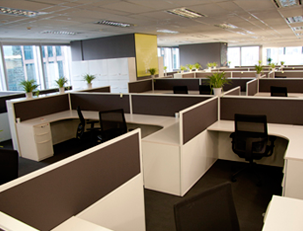 Cubículos de oficina con divisores de color marrón oscuro y sillas negras.