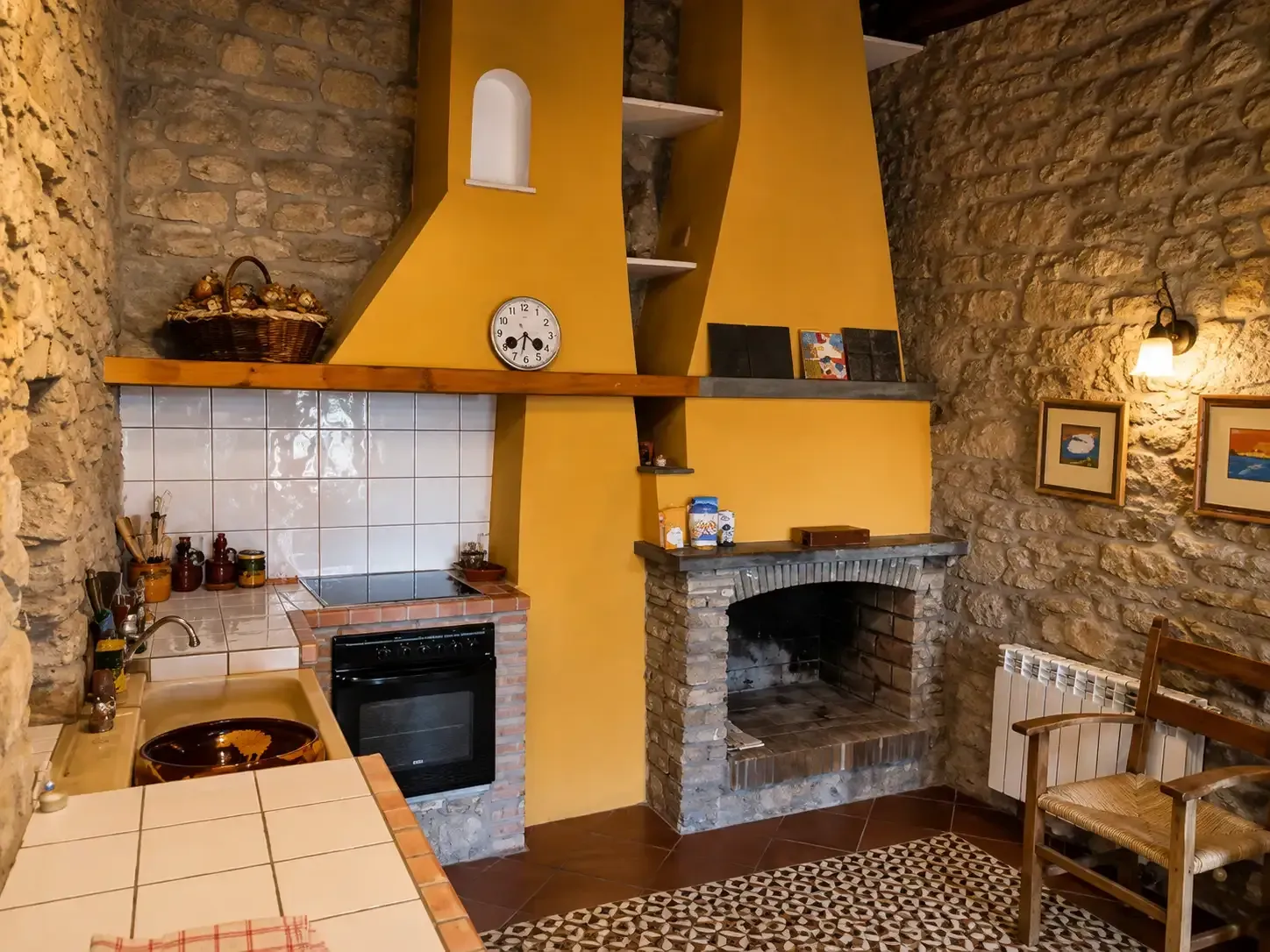 Acogedora cocina rústica con paredes de piedra, campana extractora amarilla, zona de cocina