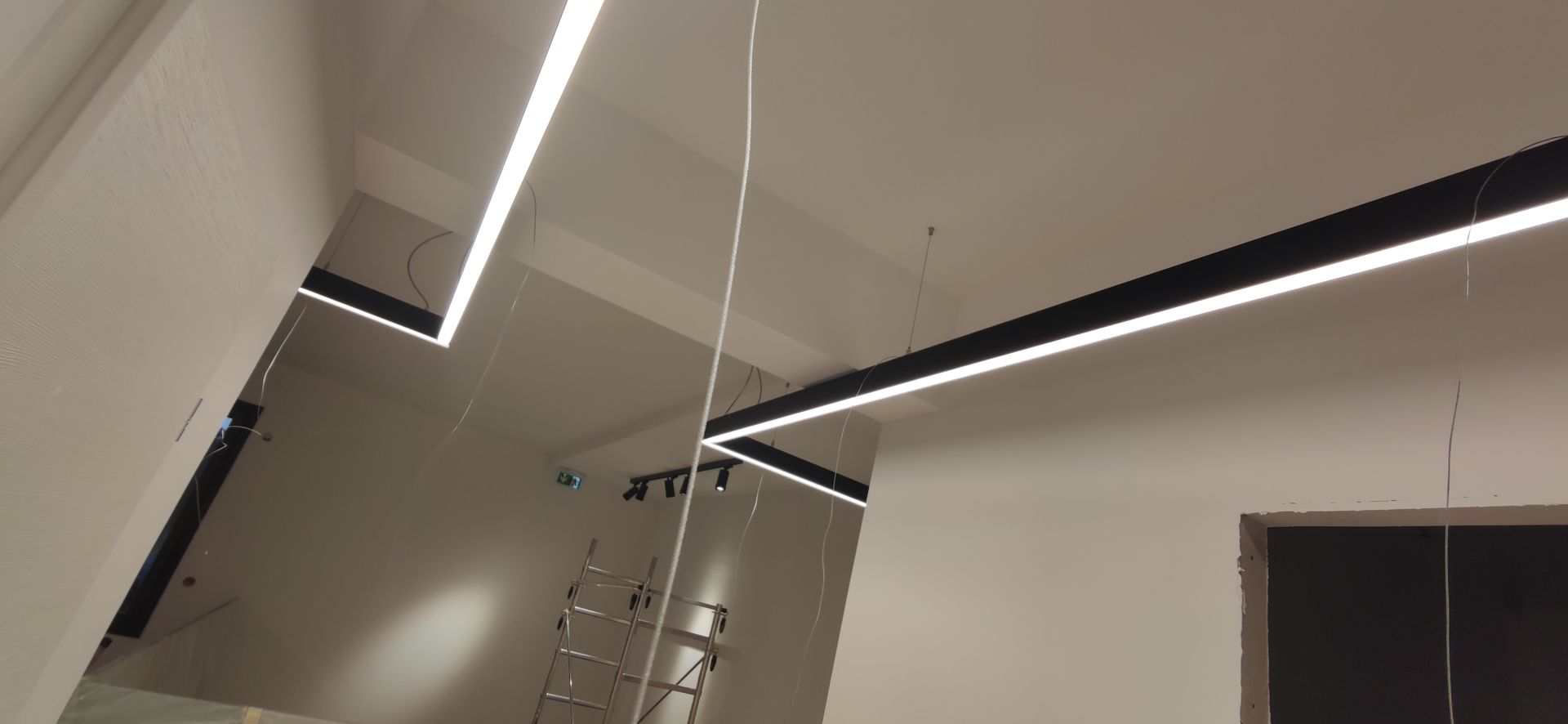 Pose de barres d'éclairage suspendues dans un couloir