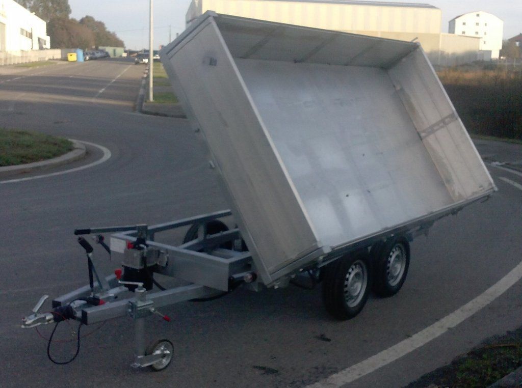 Un remolque plateado está estacionado al costado de la carretera.