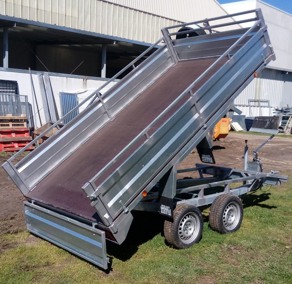 Un remolque volquete está estacionado en el césped frente a un edificio.