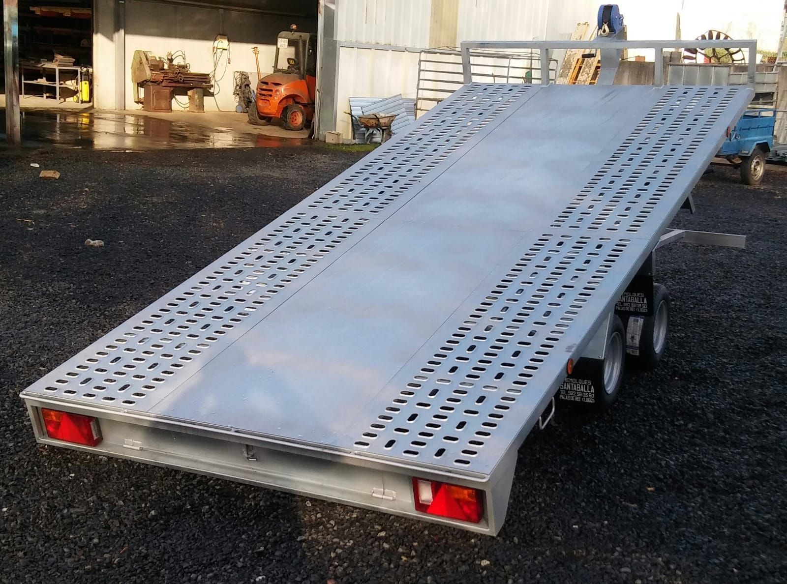 Un remolque plateado está estacionado en un lote de grava.