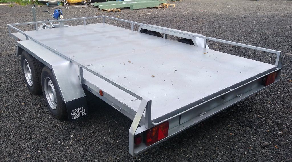 Un remolque con plataforma está estacionado en un lote de grava.