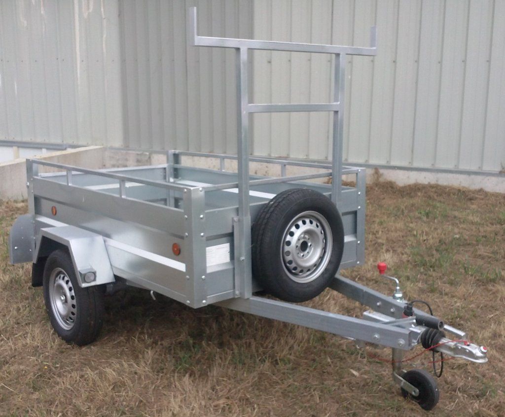 Un remolque con un neumático en la parte trasera está estacionado en el césped.