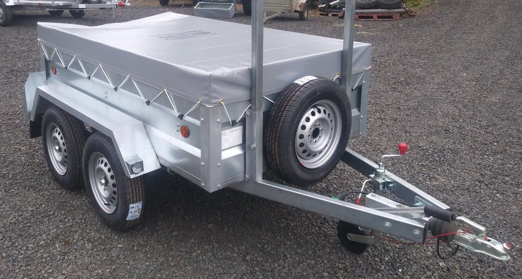 Un remolque con una lona encima está estacionado sobre grava.