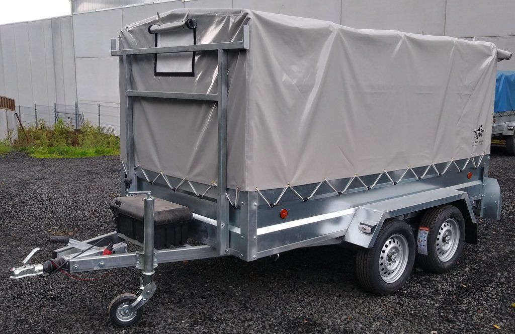 Un remolque con una lona encima está estacionado en un lote de grava.