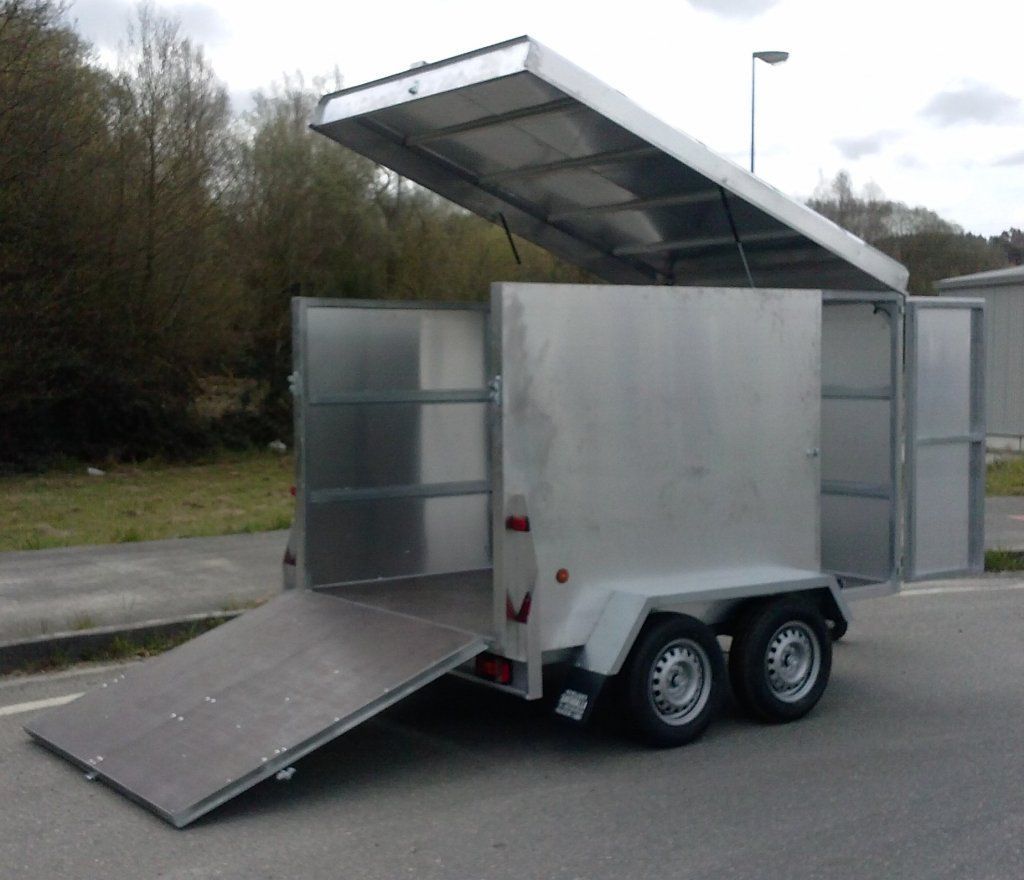 Un remolque con la tapa abierta está estacionado al costado de la carretera