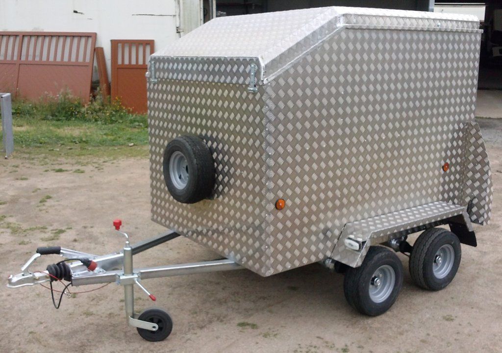 Un remolque plateado con una llanta negra en la parte trasera.