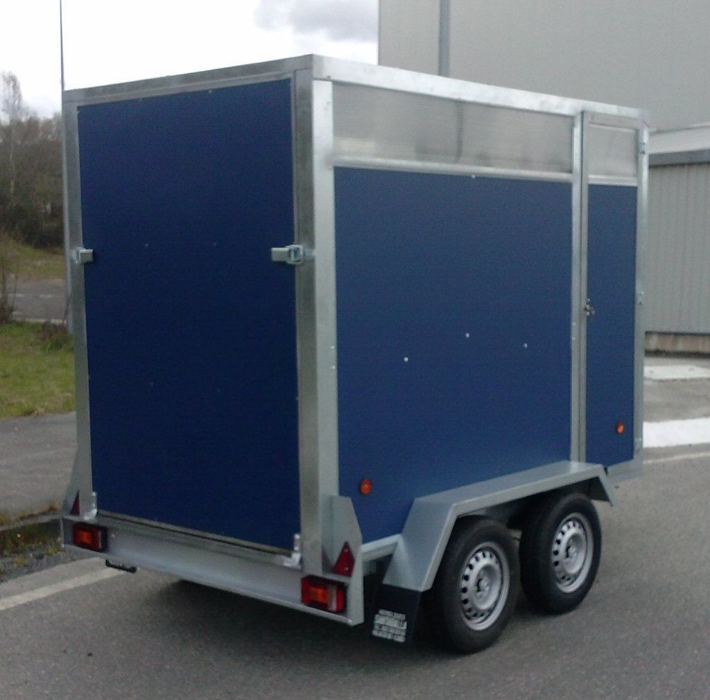 Un remolque azul está estacionado al costado de la carretera.