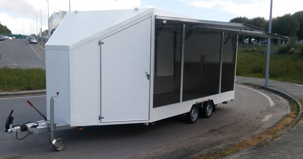 Un remolque blanco está estacionado al costado de la carretera.