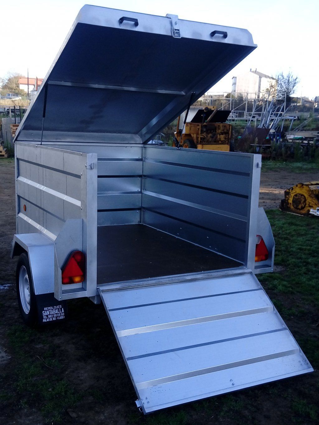 Un remolque de metal con la tapa abierta y una rampa.