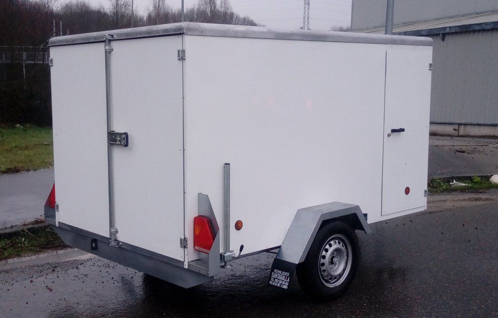 Un remolque blanco está estacionado al costado de la carretera.