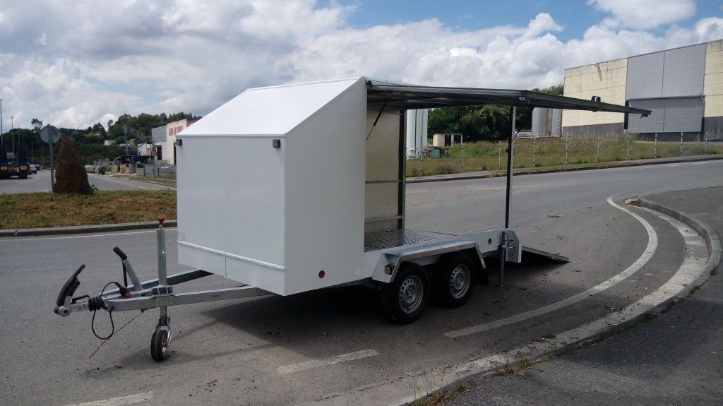Un remolque blanco está estacionado al costado de la carretera.