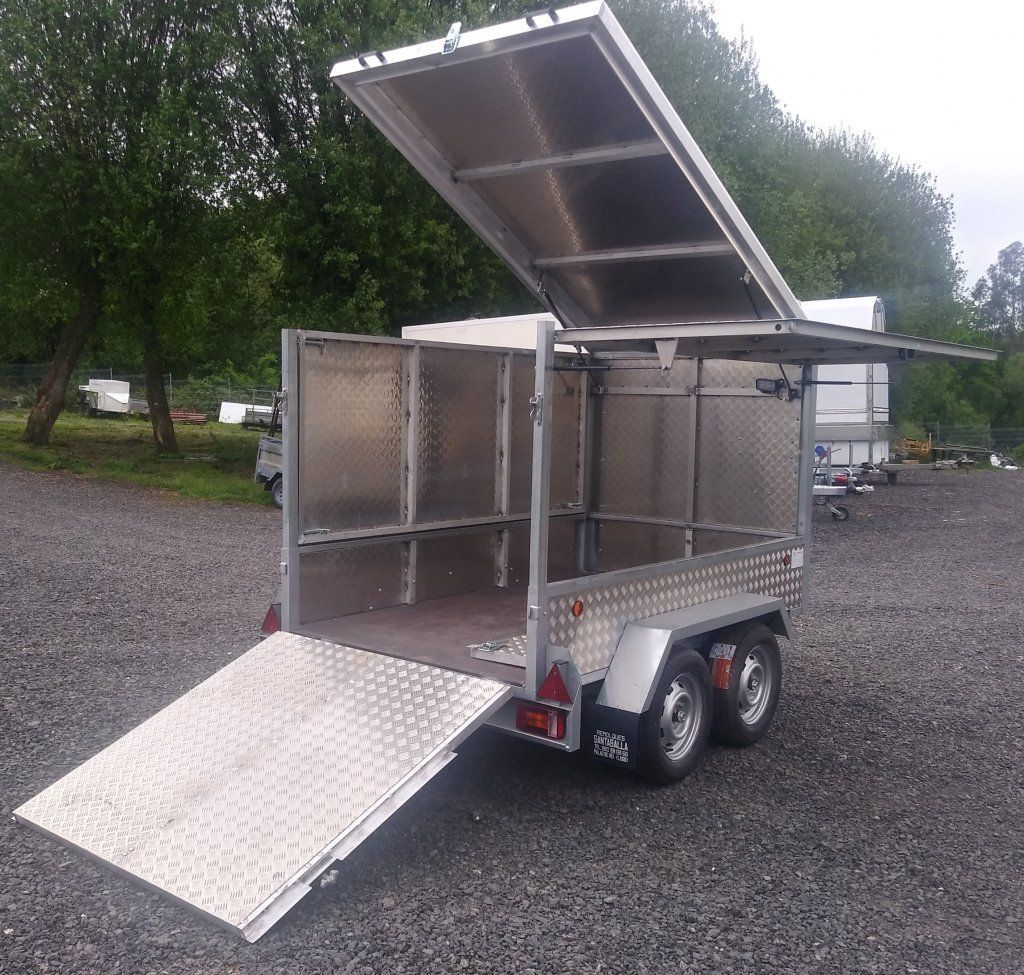 Un remolque de acero inoxidable está estacionado en un lote de grava.