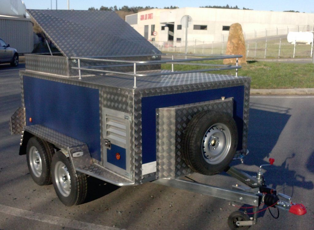 Un remolque azul y plateado está estacionado al costado de la carretera.