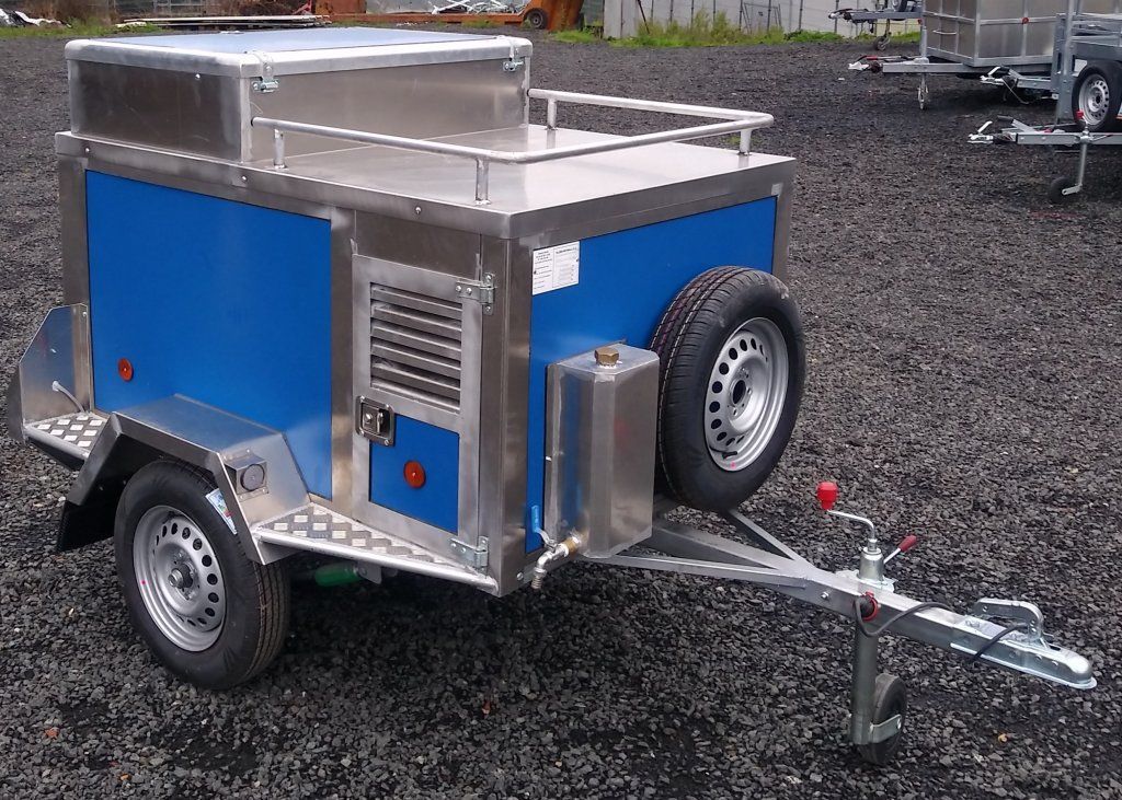 Un remolque azul y plateado está estacionado sobre grava.