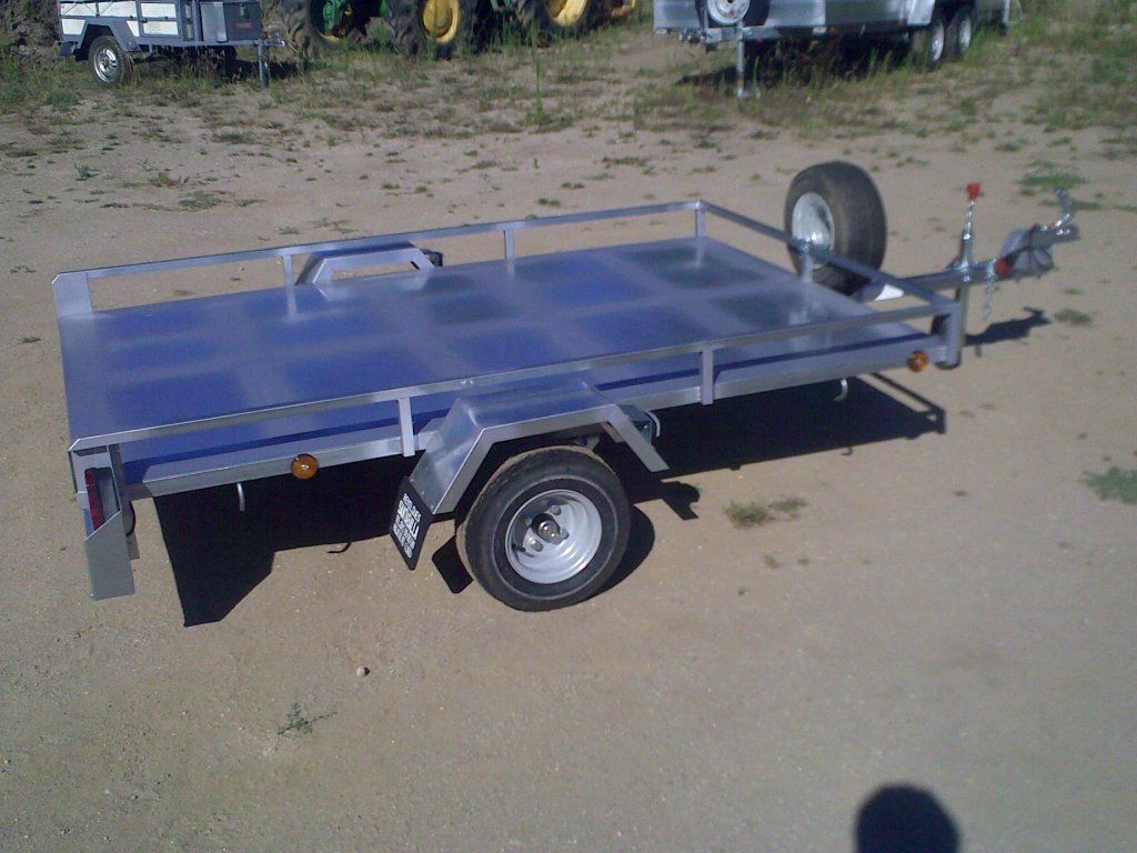 Un remolque azul está estacionado en un camino de tierra