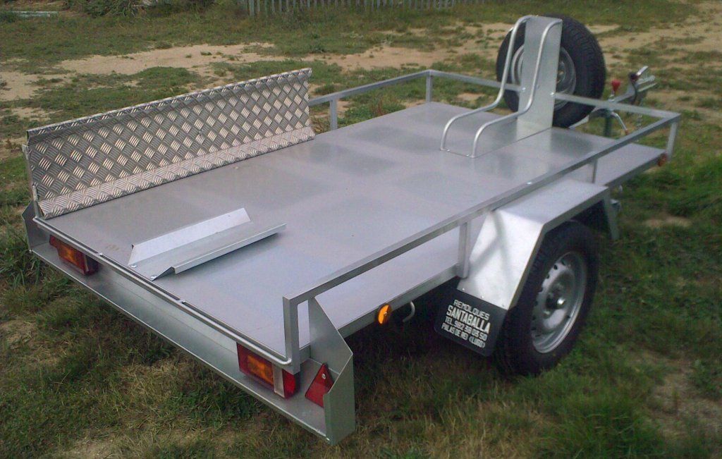 Un remolque con una motocicleta encima está estacionado en el césped.