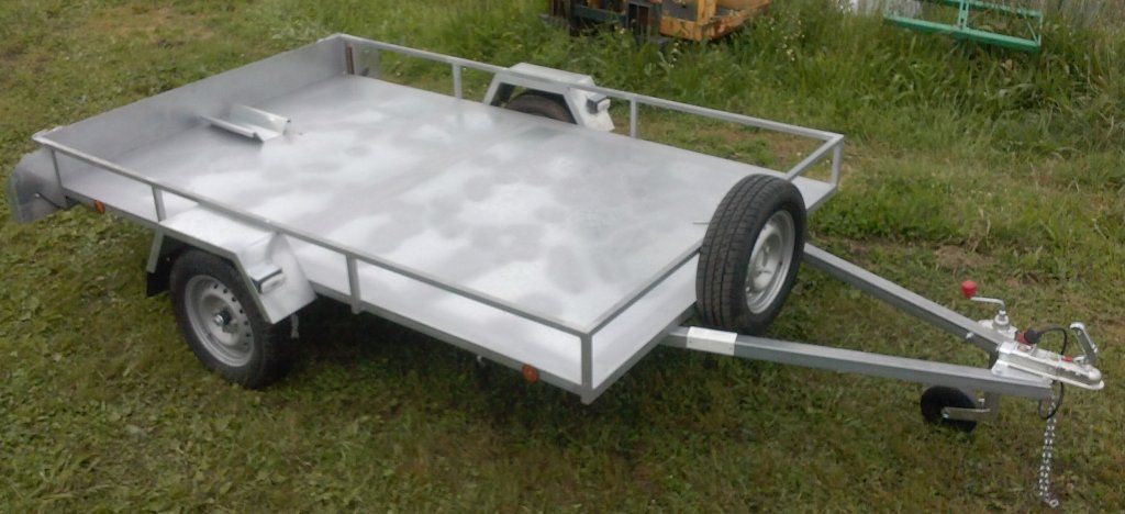 Un pequeño remolque se encuentra en la parte superior de un exuberante campo verde.