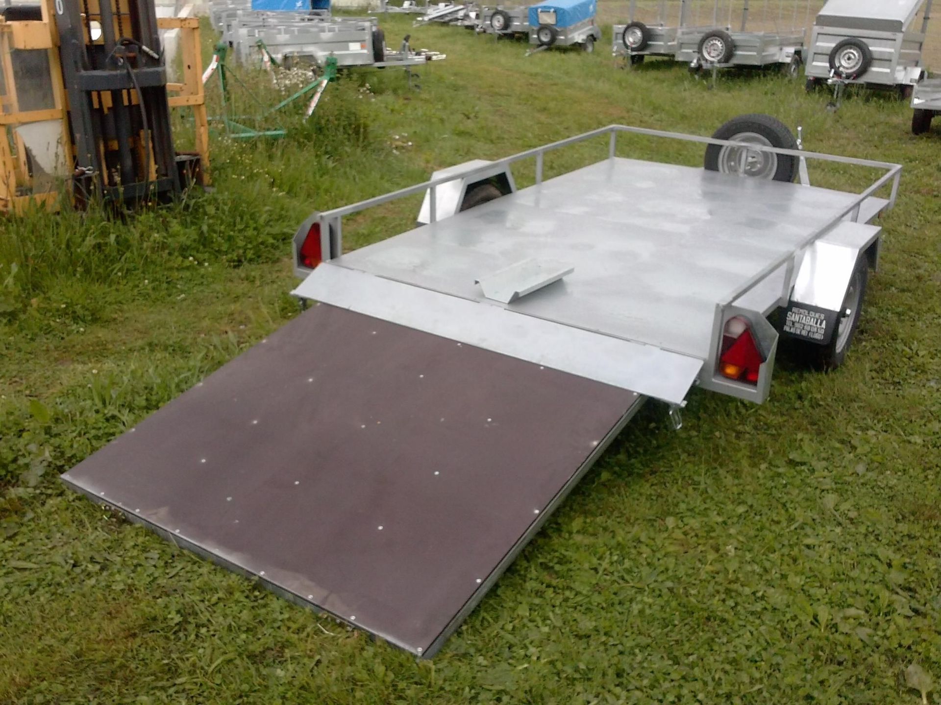 Un pequeño remolque está estacionado en un campo de hierba.