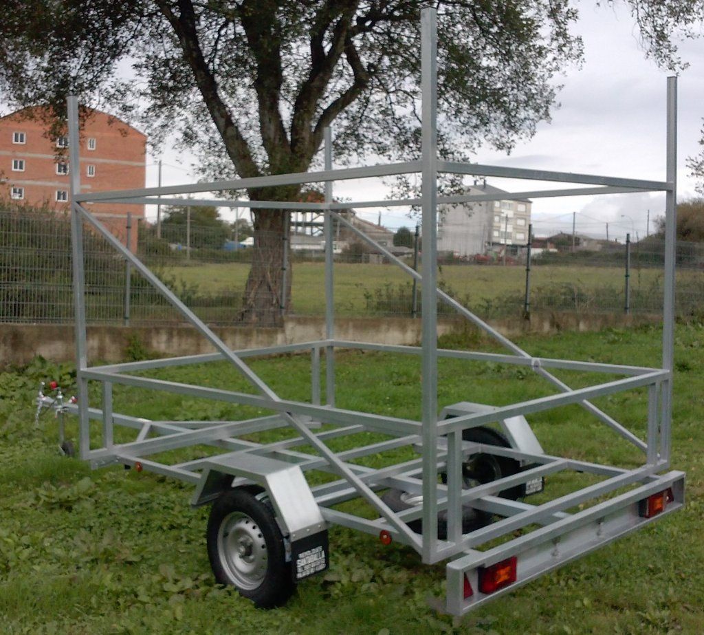 Un remolque está estacionado en el césped con un árbol al fondo.