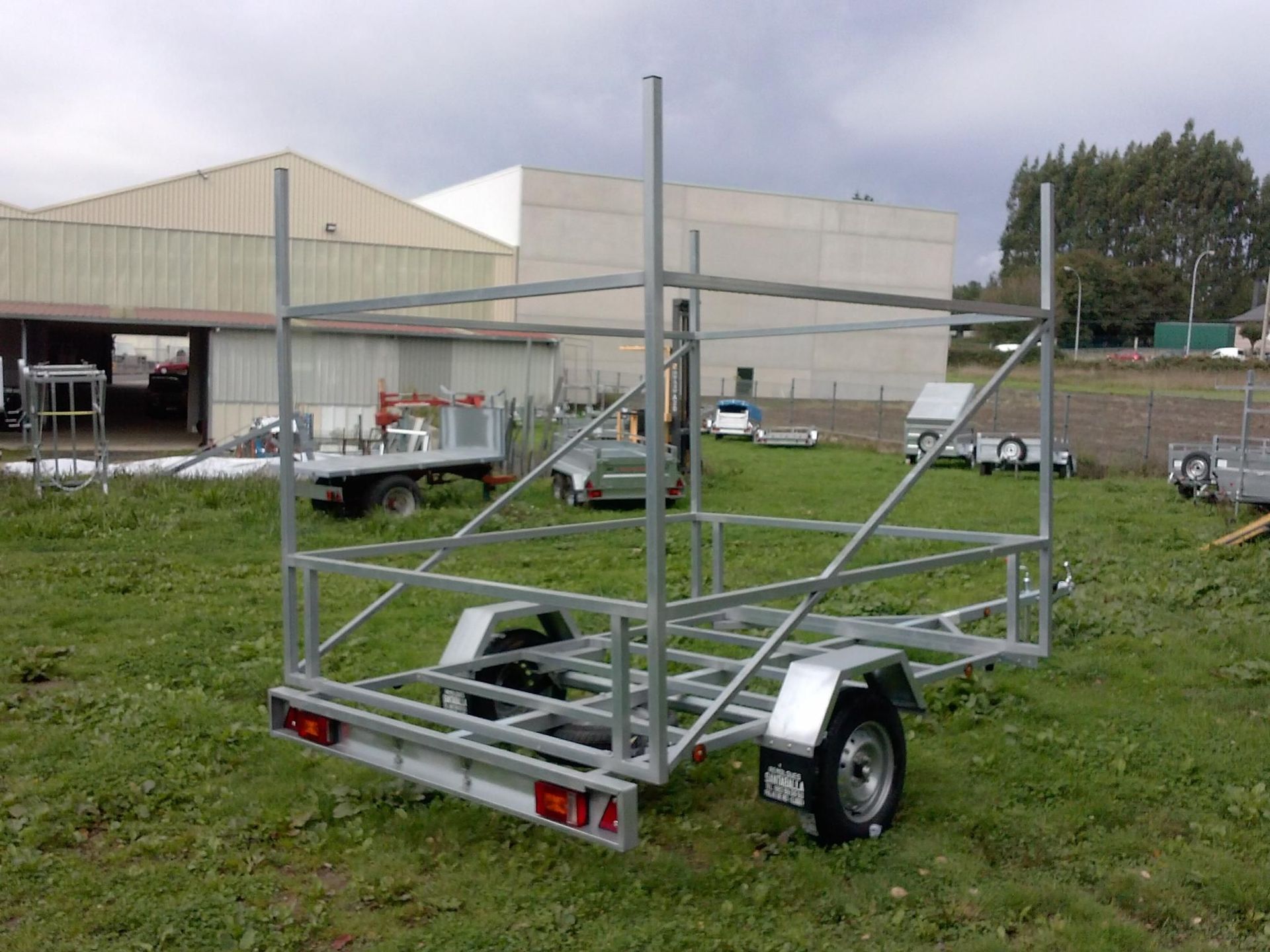 Un remolque está estacionado en un campo de hierba frente a un edificio.