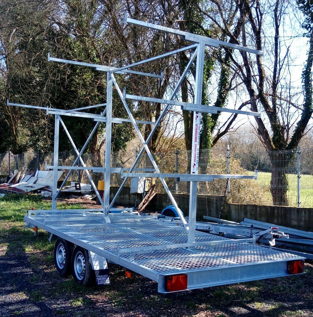Un remolque de metal está estacionado en un campo con árboles al fondo.