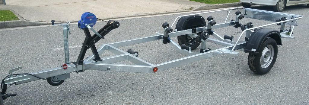 Un remolque de barco está estacionado al costado de la carretera al lado de un automóvil.