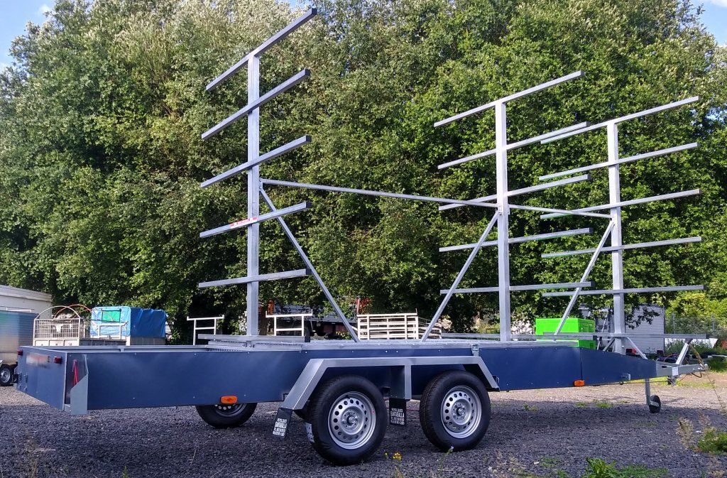 Un remolque con muchos bastidores está estacionado en un lote de grava.