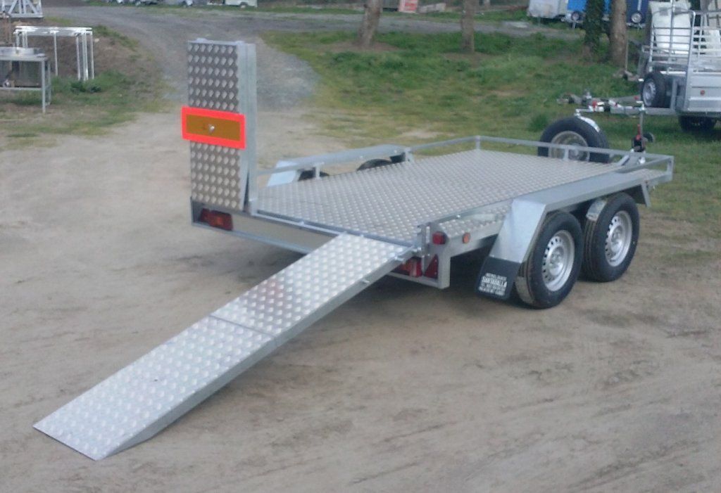 Un remolque con una rampa acoplada está estacionado en un camino de tierra.