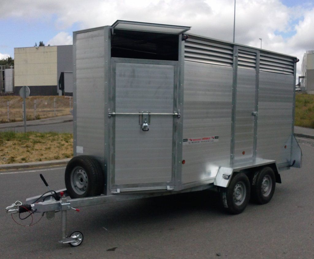 Un remolque plateado está estacionado al costado de la carretera.