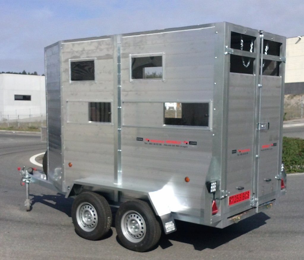 Un remolque plateado está estacionado al costado de la carretera.