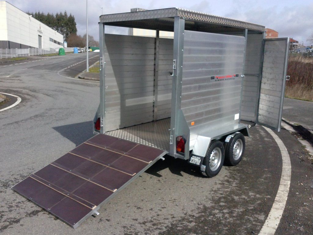 Un remolque con las puertas abiertas está estacionado al costado de la carretera.