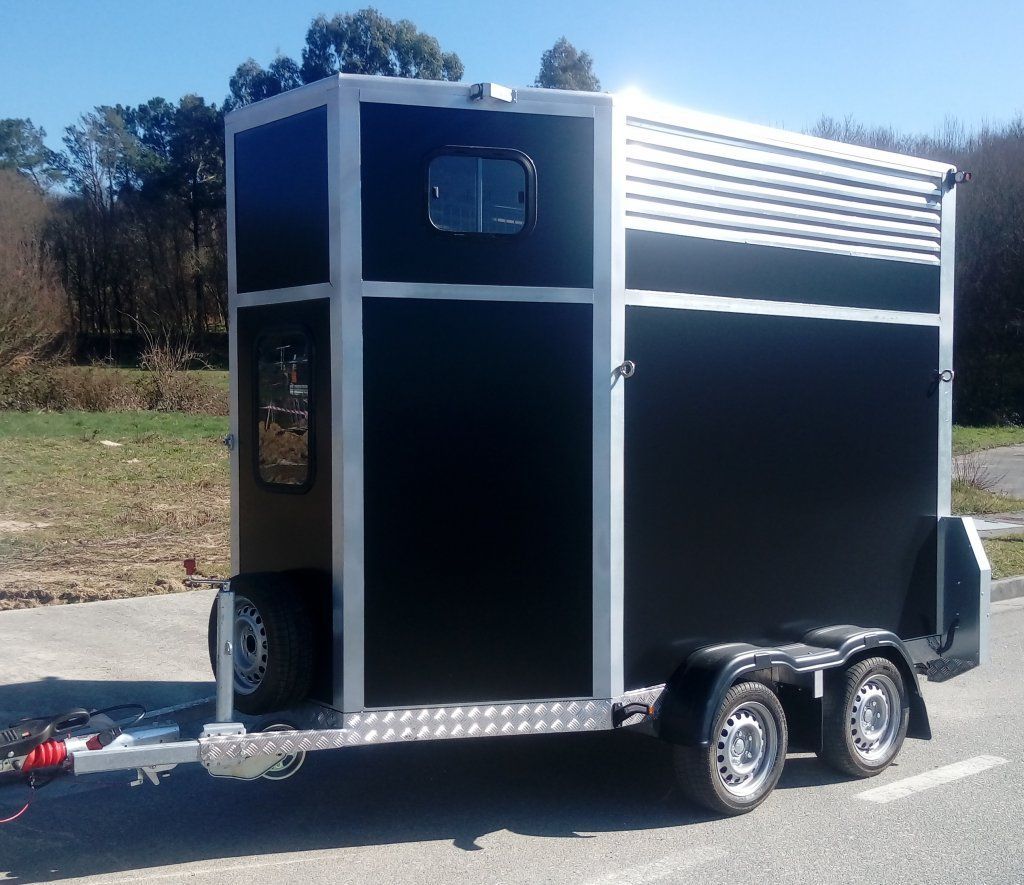 Un remolque negro está estacionado al costado de la carretera.