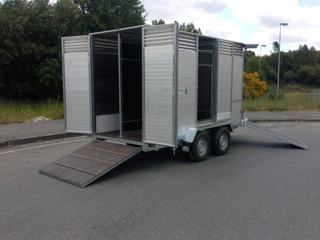 Un remolque con las puertas abiertas está estacionado al costado de la carretera.