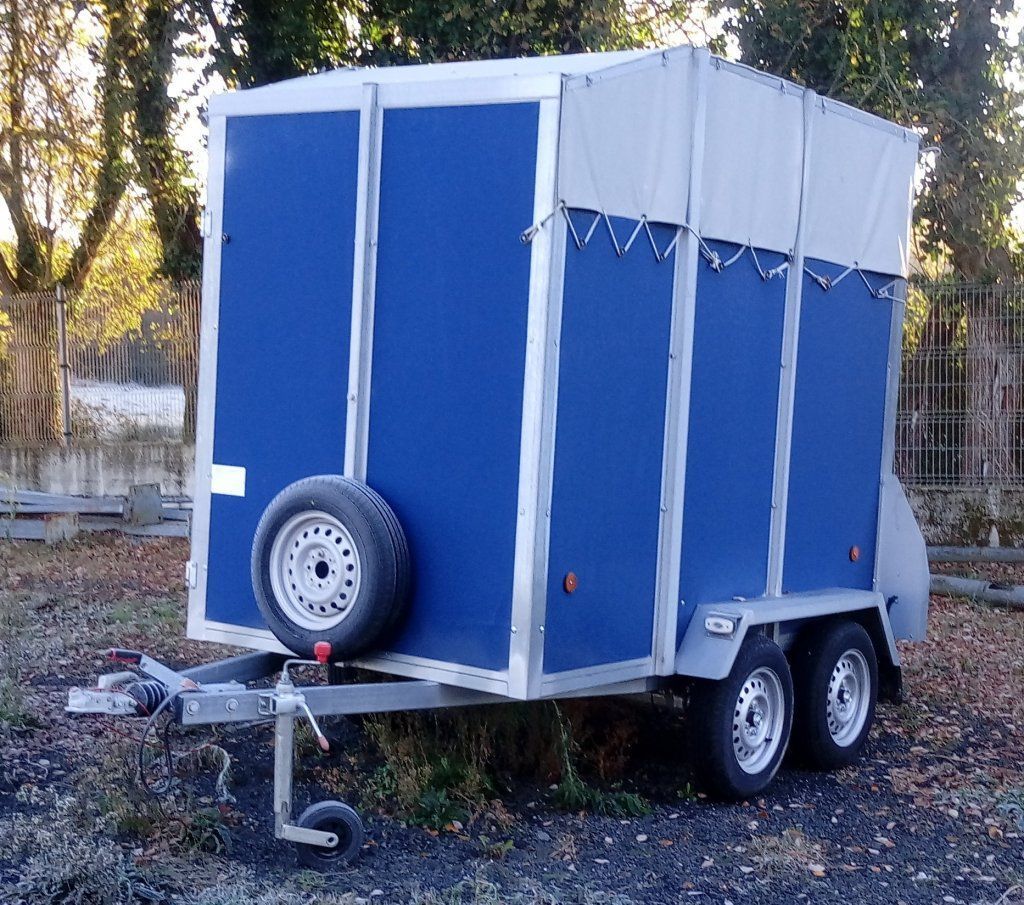 Un remolque azul y blanco con una llanta en el costado