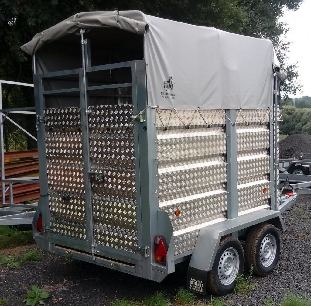 Un remolque plateado con una lona blanca encima.